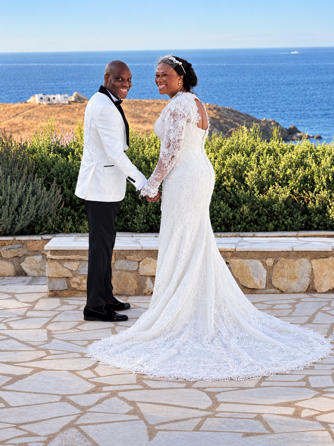 Smiling bride and groom in white wedding attire by the sea
