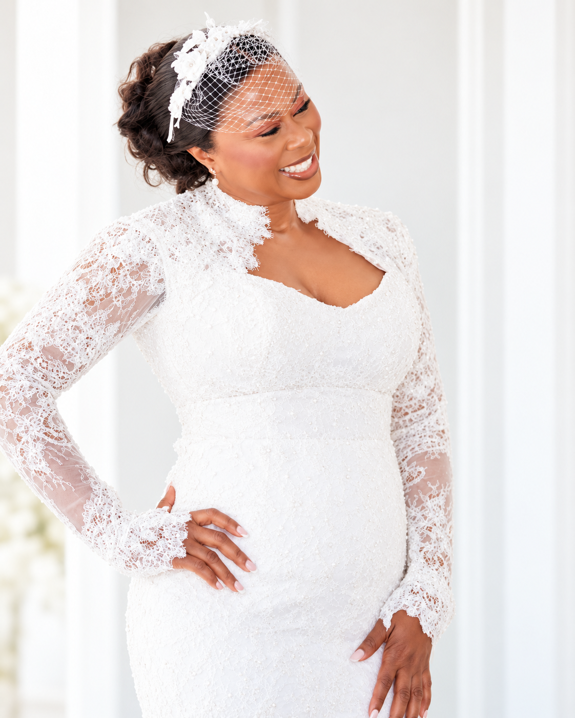 Close portrait of a smiling bride in a white lace gown and birdcage veil