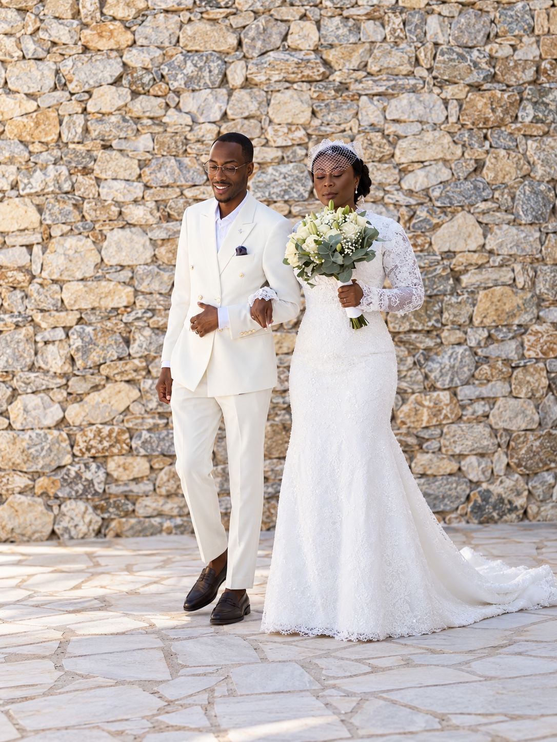 Bride and groom walking together beside a stone wall